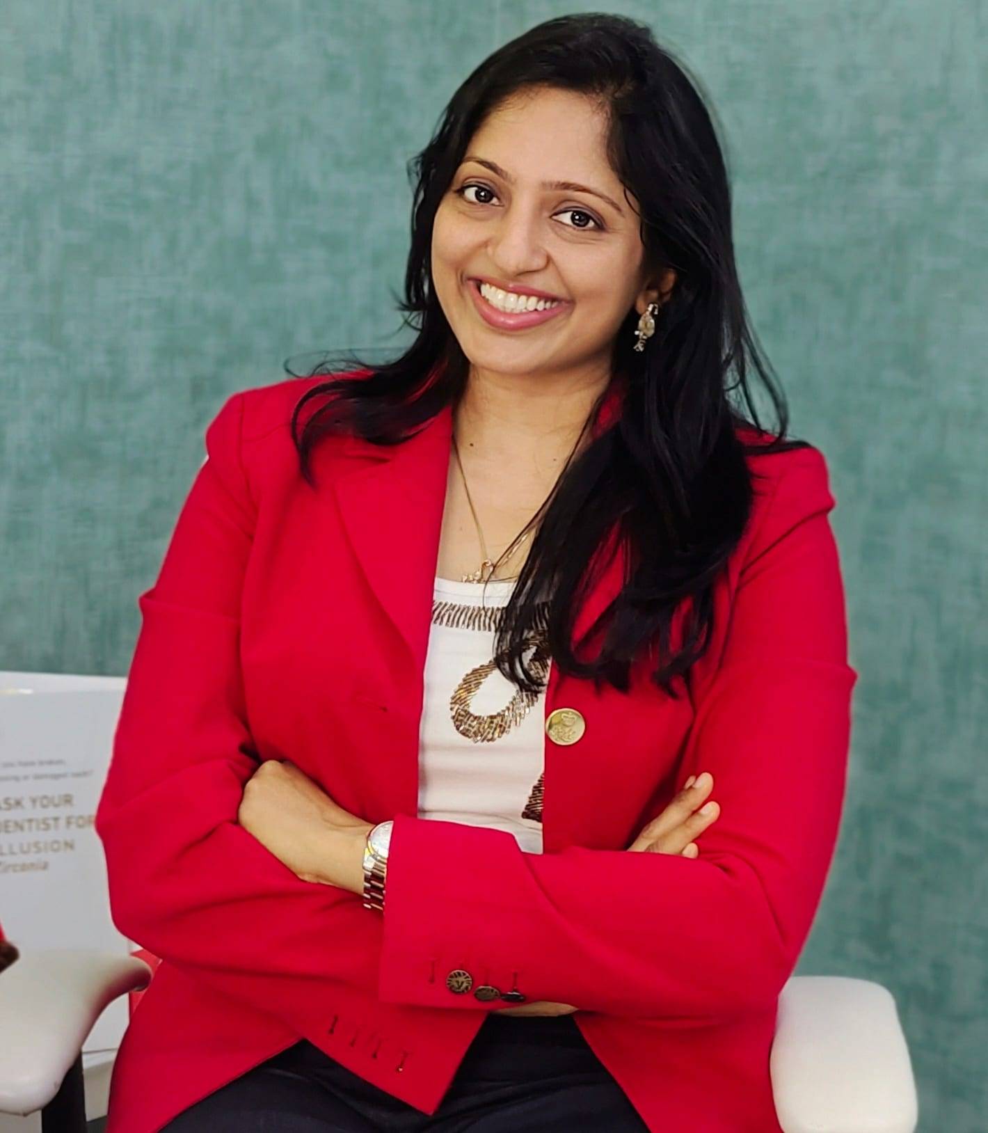 Dr. Vaishali Machhi smiling in a red blazer in the clinic