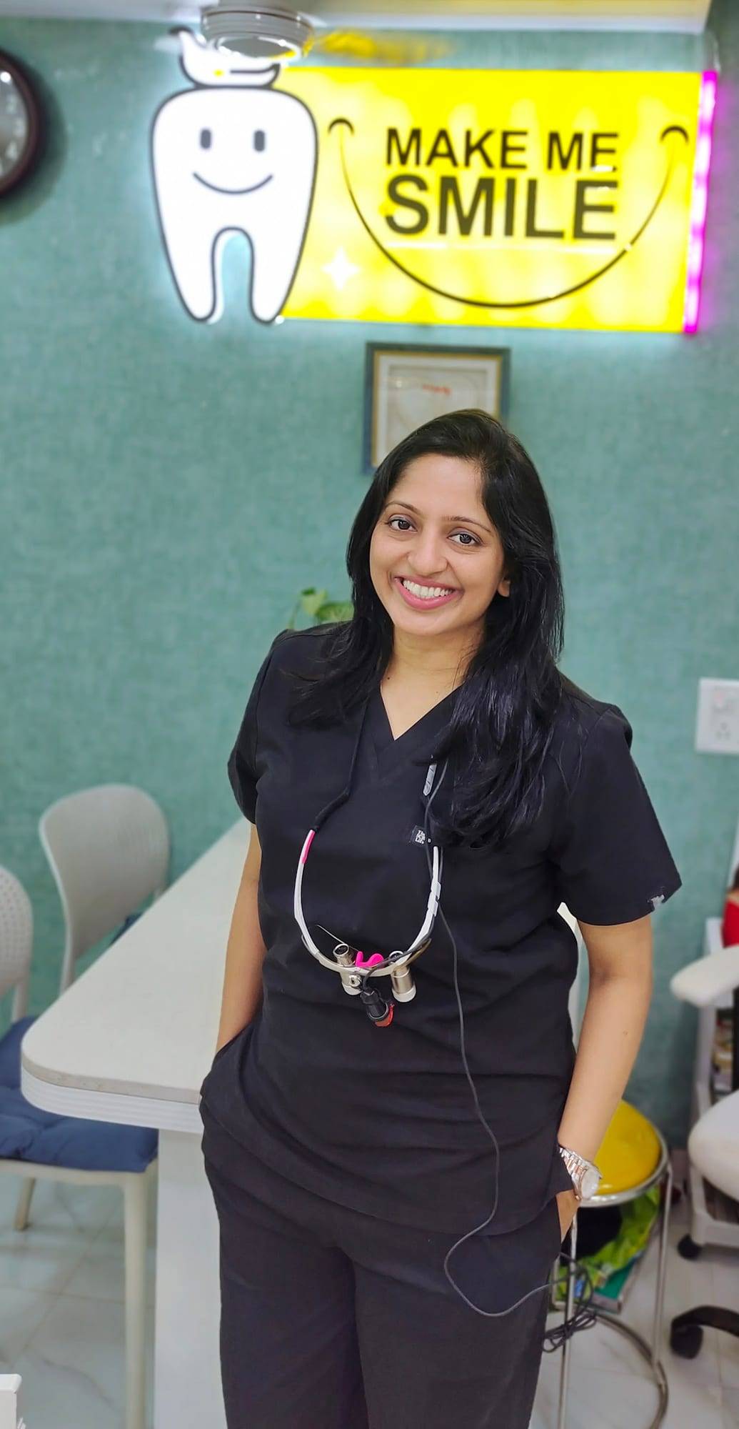 Dr. Vaishali Machhi in scrubs beneath the illuminated Make Me Smile sign